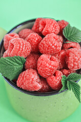 Fresh ripe raspberries in a green jar. Close up.