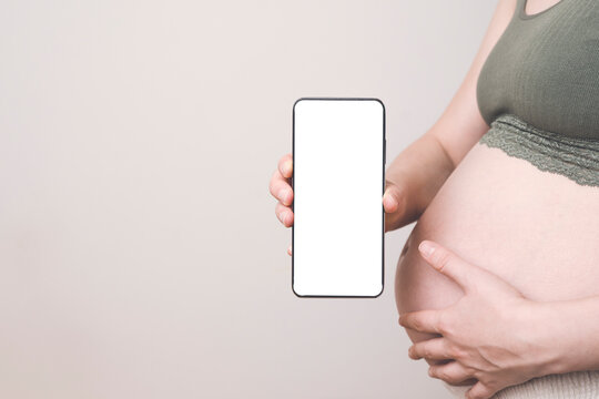 Pregnant woman holding a phone with a blank screen, mock-up. Pregnancy apps, gadgets, move and push tracking, diet background