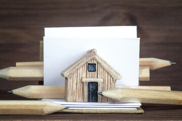 Miniature wooden house model, sketchbook and pencils