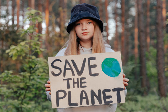 Save the Planet banner holding in young children hands. Inspiring teen girl making protest about climate change, plastic problems, global warming, pollution in forest park. Climate Strike. Eco