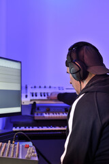 Man with headphones working in the studio on the creation and recording of music. Musician composes and works with electronic instruments to create sound.