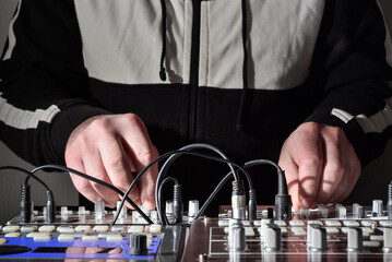 Hands at work with electronic musical instruments and synthesizers to generate and create sound for...