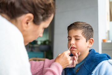 Mother doing an antigen test to her son at home