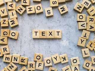 Top view of the word TEXT. Wooden letters add up to words.