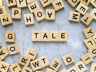 Top view of the word TALE. Wooden letters add up to words.