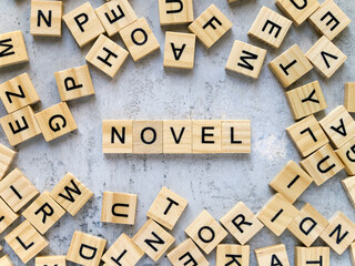 Top view of the word NOVEL. Wooden letters add up to words.