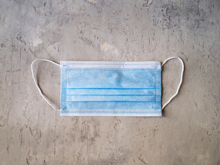 Top view of a new blue surgical mask on a gray background.