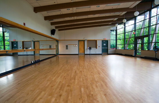 A dance ballet studio,with a sprung wooden floor, barre and wall mirrors.