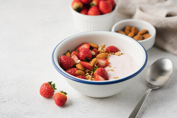 Strawberry yogurt with fresh berries, homemade granola, almonds in bowl. Healthy breakfast on light...