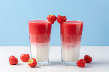 Protein rich smoothies with yogurt and frozen strawberries in glass on light blue background. Concept of drinks for lovers on Valentine's Day. Bright berry as a symbol of the heart