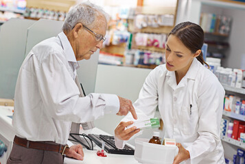 She's always there for client queries. Shot of a young pharmacist helping an elderly customer at...