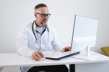 Male doctor in the office working on the computer