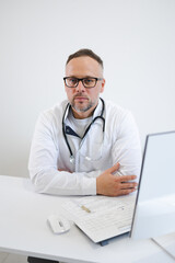 Portrait of serious male doctor sitting at his workplace in office