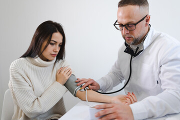 Male doctor measures blood pressure to the female patient