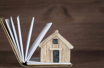 Tiny toy house standing on a small open book
