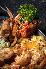 Homemade Fried eggs with king prawns, Norway lobsters, prawns, garlic and spices