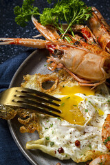 Homemade Fried eggs with king prawns, Norway lobsters, prawns, garlic and spices