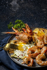 Homemade Fried eggs with king prawns, Norway lobsters, prawns, garlic and spices