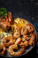 Homemade Fried eggs with king prawns, Norway lobsters, prawns, garlic and spices