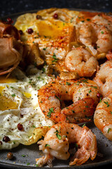 Homemade Fried eggs with king prawns, Norway lobsters, prawns, garlic and spices