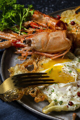 Homemade Fried eggs with king prawns, Norway lobsters, prawns, garlic and spices