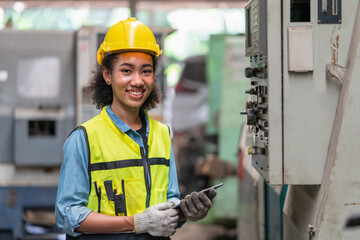 Portrait Asian female Engineer with yellow helmet using tablet working operating machine at factory...