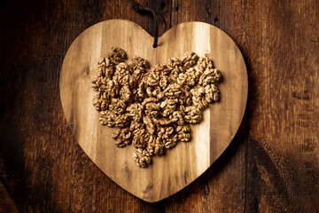 Peeled walnuts. On a wooden board in the shape of a heart. Healthy food. Natural background.