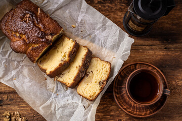 Banana bread sliced. Cup with herbal tea. Dark wooden background.