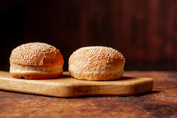 Two hamburger buns. Sesame seeds on top. Wooden background. Food concept.