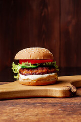 Hamburger with grilled meat cheese, green salad and tomato. Wooden background. Hamburger Day.