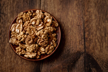 Peeled walnuts on a plate. Dark wooden background. Vegetarian, healthy food. View from above. Place for your text.