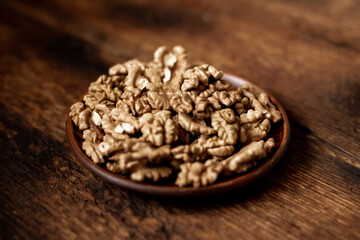 Peeled walnuts on a plate. Dark wooden background. Vegetarian, healthy food.
