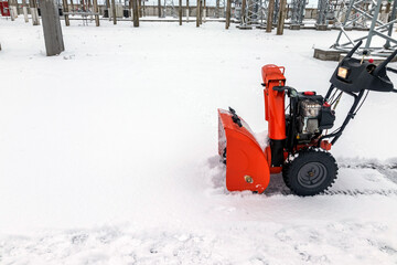 The snow-covered sidewalk is cleared of snowdrifts with the help of mini-snow removal equipment....