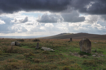 Ancient stone circle under Great Staple Tor with dark cloudy sky overhead, Dartmoor National Park,...