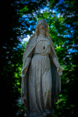 Fototapeta na wymiar Virgin Mary ancient stone statue. Vintage sculpture of sad woman in grief