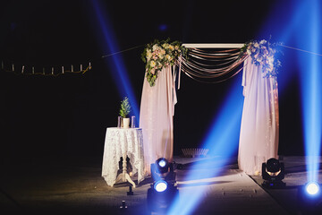 Night ceremony with light and fire show. The wedding arch is decorated with flowers at night...