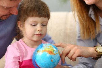 Parents show world globe to child closeup