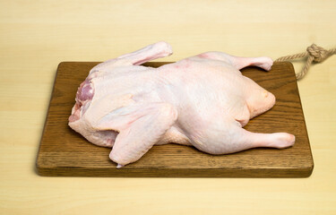 Fresh duck carcass lies on a wooden cutting board on the table