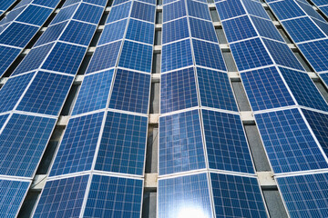 Obraz premium Aerial view of solar power plant with blue photovoltaic panels mounted on industrial building roof for producing green ecological electricity. Production of sustainable energy concept
