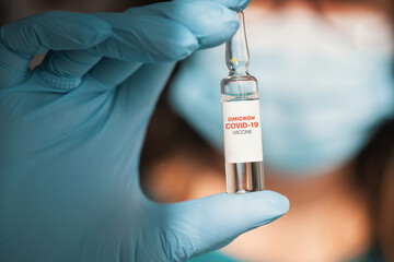Coronavirus modified omicron vaccine in hand with blue protective gloves.