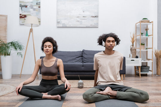 Young african american couple in headphones meditating at home.
