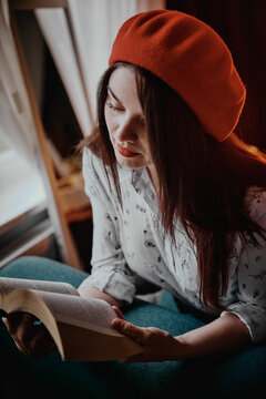 a girl with dark long hair in a red beret and a white blouse, retro style. Indoor soft light