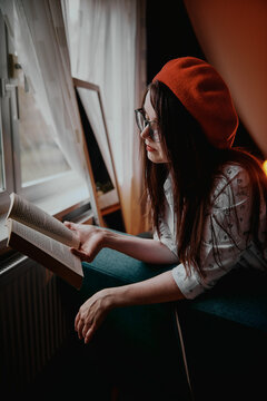 a girl with dark long hair in a red beret and a white blouse, retro style. Indoor soft light