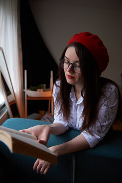 a girl with dark long hair in a red beret and a white blouse, retro style. Indoor soft light