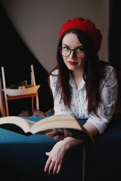 a girl with dark long hair in a red beret and a white blouse, retro style. Indoor soft light