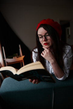 a girl with dark long hair in a red beret and a white blouse, retro style. Indoor soft light