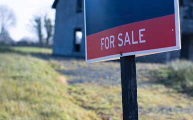 for sale sign with a partially completed house in the background