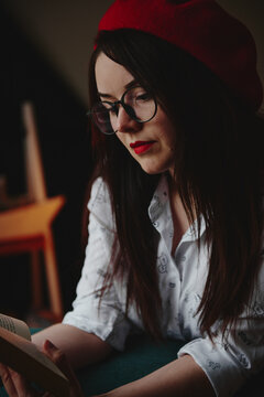 a girl with dark long hair in a red beret and a white blouse, retro style. Indoor soft light
