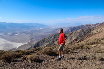 Naklejka premium A Spunky and Adventurous Man Exploring the Dantes View in Death Valley, California Overlooking the Eroded Valley from the Cliff Exploring Earth Science Forces