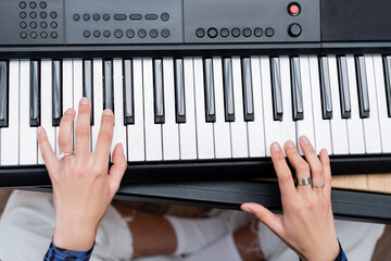 Cropped view of african american woman playing synthesizer at home.
